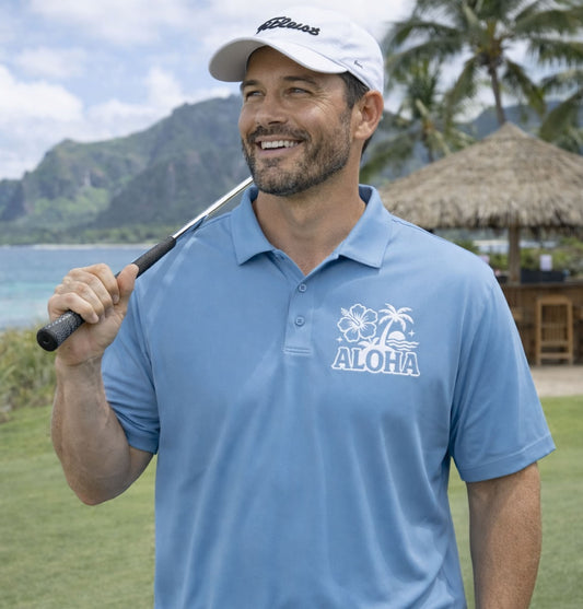 Man in golf polo holding a golf club on with mountains and palm trees in the background
