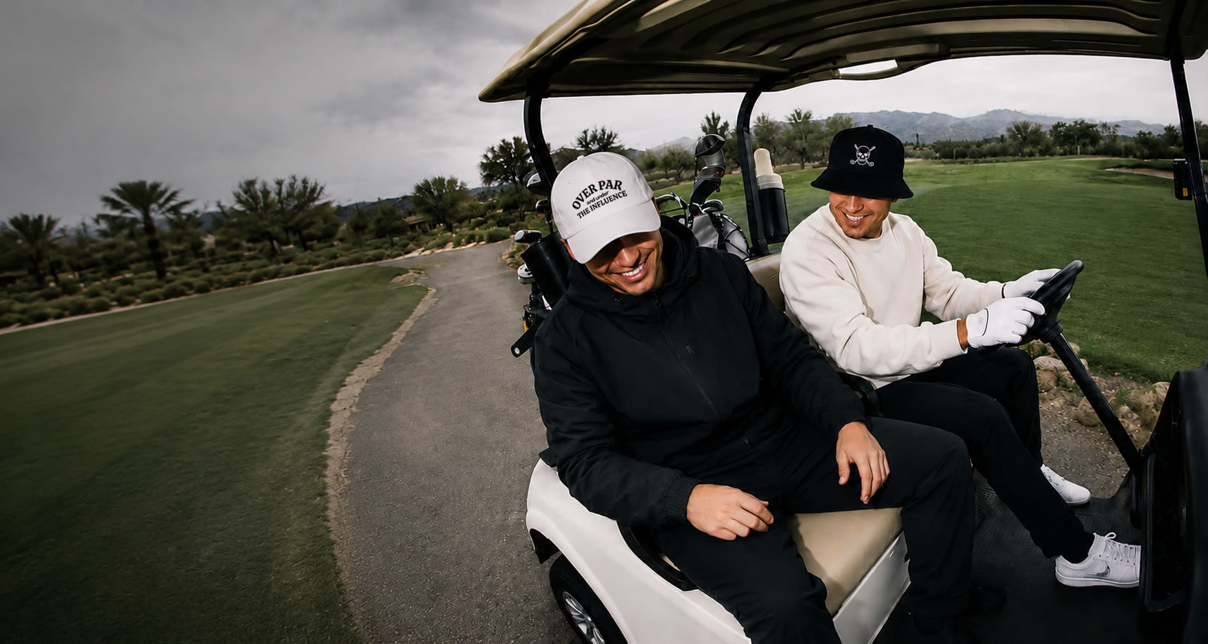 Two people in a golf cart on a golf course wearing a golf apparel and hats.